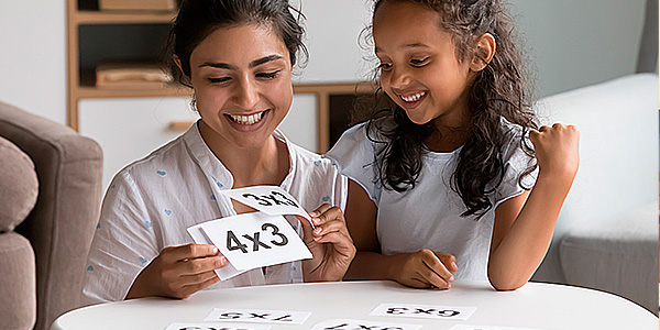 Mãe e filha com papel de continhas matemáticas na mão 