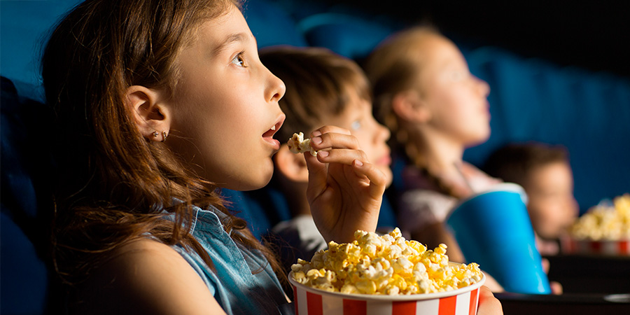 menina comendo pipoca e vendo filme infantil 