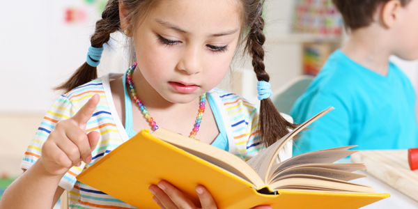 Menina lê livro e o Colégio Classe A sabe como incentivar a leitura infantil. 