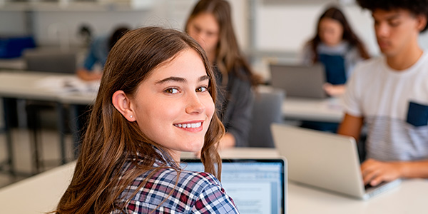 Menina sorri para a foto enquanto estuda. 