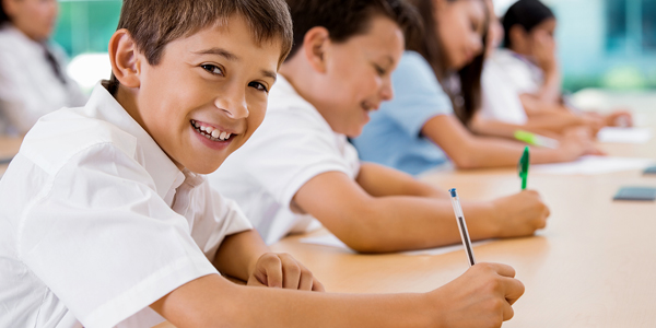 meninos do ensino fundamental, sorrindo, com caneta e caderno nas mãos