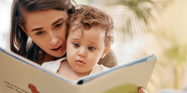 uma mãe com o filho pequeno no colo lendo uma história infantl