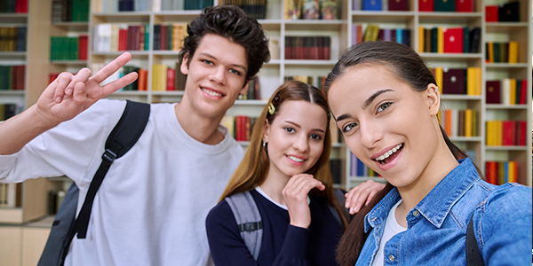 Três adolescentes na biblioteca fazendo self 